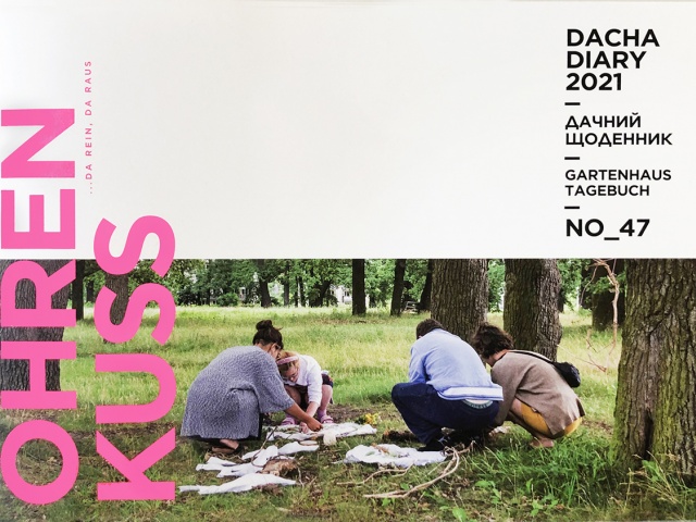 4 Personen hocken zwischen großen, alten Bäumen und gestalten ein Kunstwerk aus Naturmaterialien. Auf dem Cover steht der Name des Magazins, Ohrenkuss, und der Name der Ausgabe, Dacha Diary.