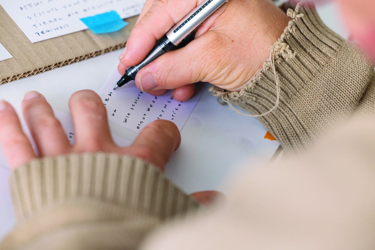 Jemand schreibt mit der Hand, man sieht nur die Hände, Stift und Papier.