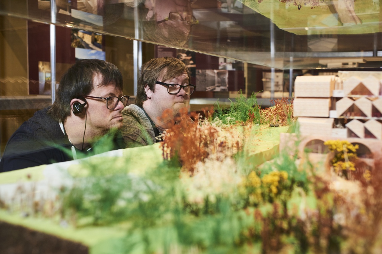 2 Ohrenkuss-Autoren betrachten ein Exponat in einem Schaukasten. Sie tragen Kopfhörer, um der Führung zuzuhören. Sie sind konzentriert.