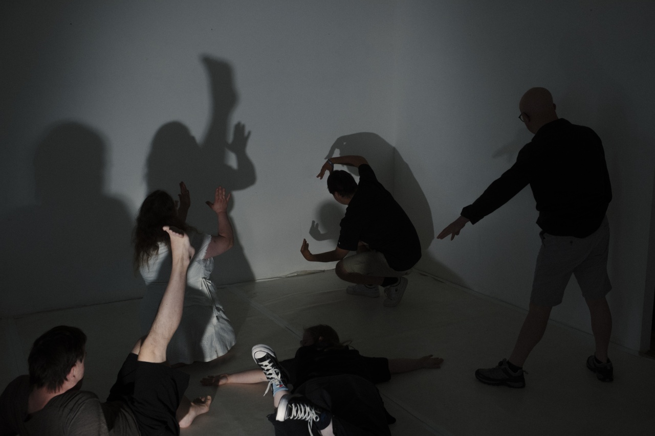 Mehrere Menschen mit Down-Syndrom bewegen sich im Raum. Ihre Schatten sind an der weißen Wand zu sehen.
