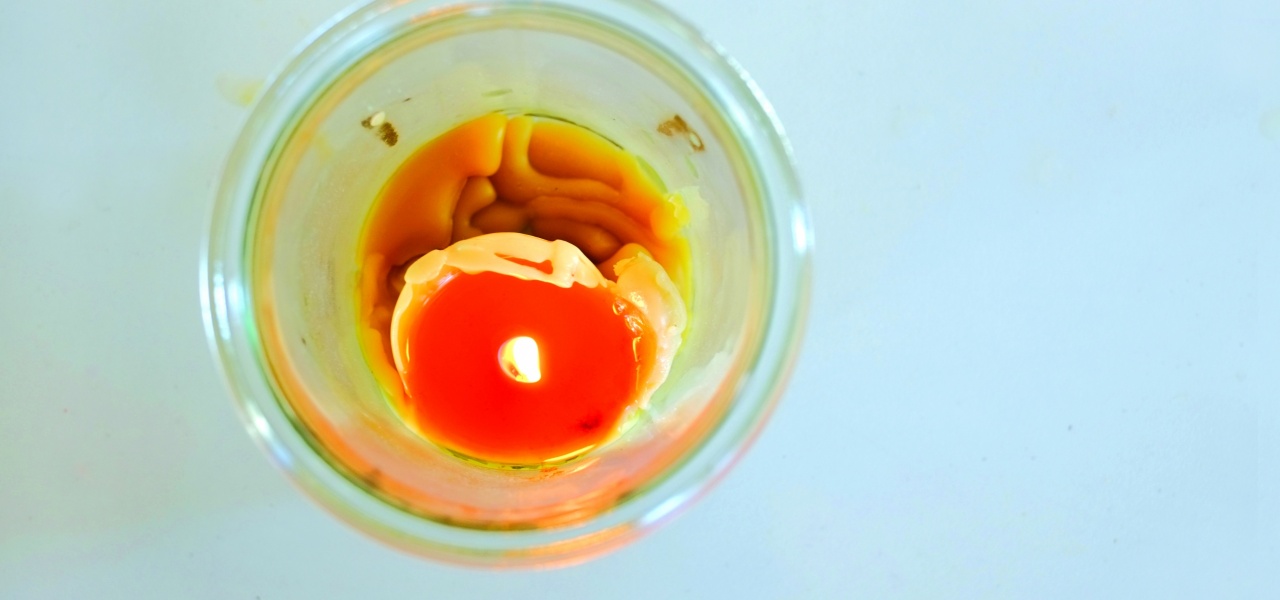 Eine gelbe Kerze brennt in einer Schale, Ansicht von oben