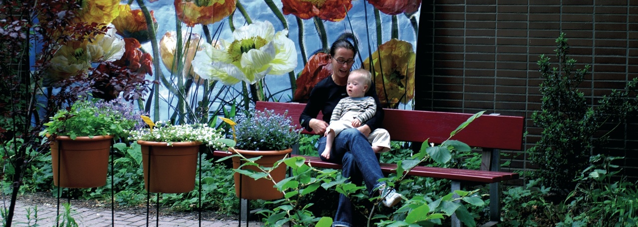 Eine Mutter mit ihrem Baby mit Down-Syndrom sitzt auf einer Bank