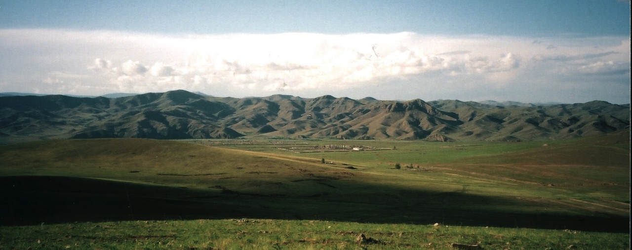 Landschaftsbild, im Hintergrund sieht man Berge und Wolken