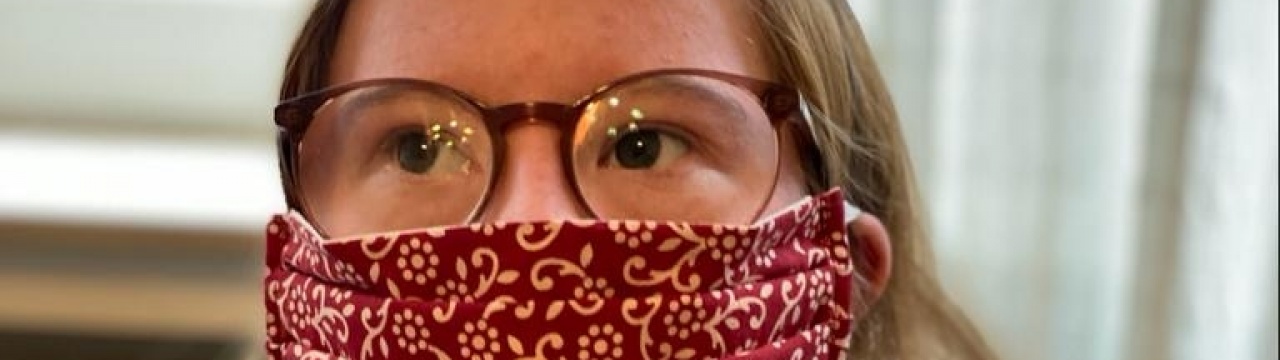 Eine junge Frau mit Doprivatwn-Syndrom trägt Brille und Atemschutzmaske