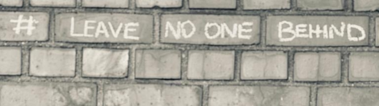 Kreideschriftzug an einer Mauer: Leave None behind