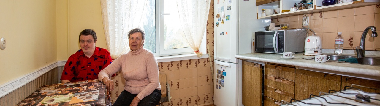 Ein Mann mit Down-Syndrom und seine Mutter sitzen eng nebeneinander in ihrer Küche in Kyjiw.