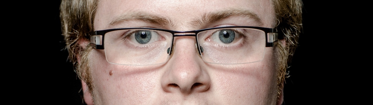 Die Augen eines Mannes mit Down.Syndrom hinter einer schmalen Brille