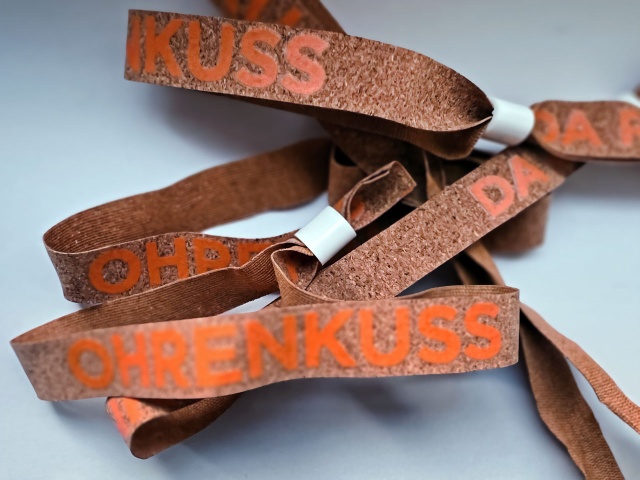 Party-Bändchen aus Kork mit dem Ohrenkuss-Schriftzug in orange