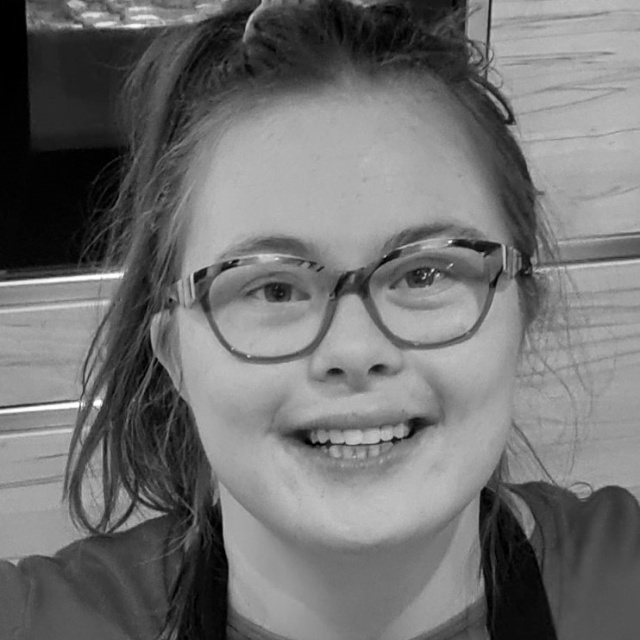 Eine junge Frau mit Down-Syndrom mit Pferdeschwanz und Brille